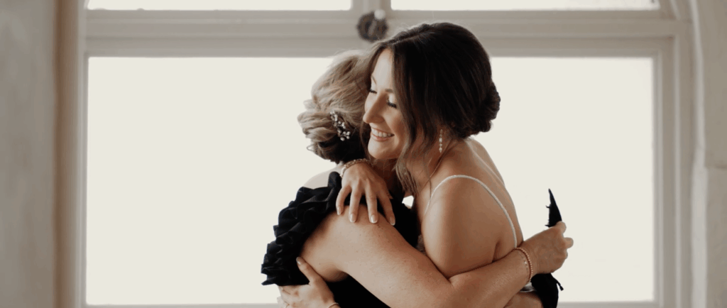 Bride warmly hugs her mother, capturing a heartfelt and emotional moment before the wedding ceremony.