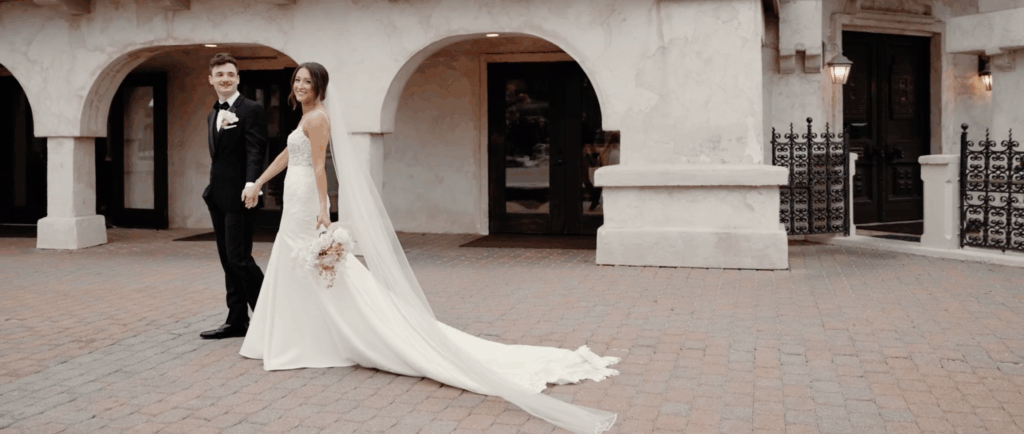 Newlyweds hold hands and walk around their outdoor wedding venue in Houston, TX.