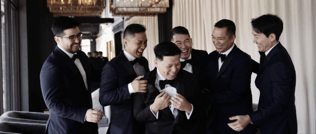 Groom laughing and enjoying a joyful moment with his groomsmen before the wedding ceremony.
