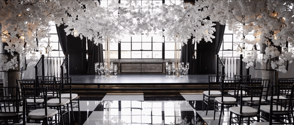 Elegant indoor wedding ceremony space featuring floral arrangements along the aisle and an altar adorned with flowers and soft lighting.