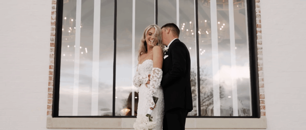 Bride laughing brightly while groom whispers in her ear, capturing a candid and playful wedding moment.