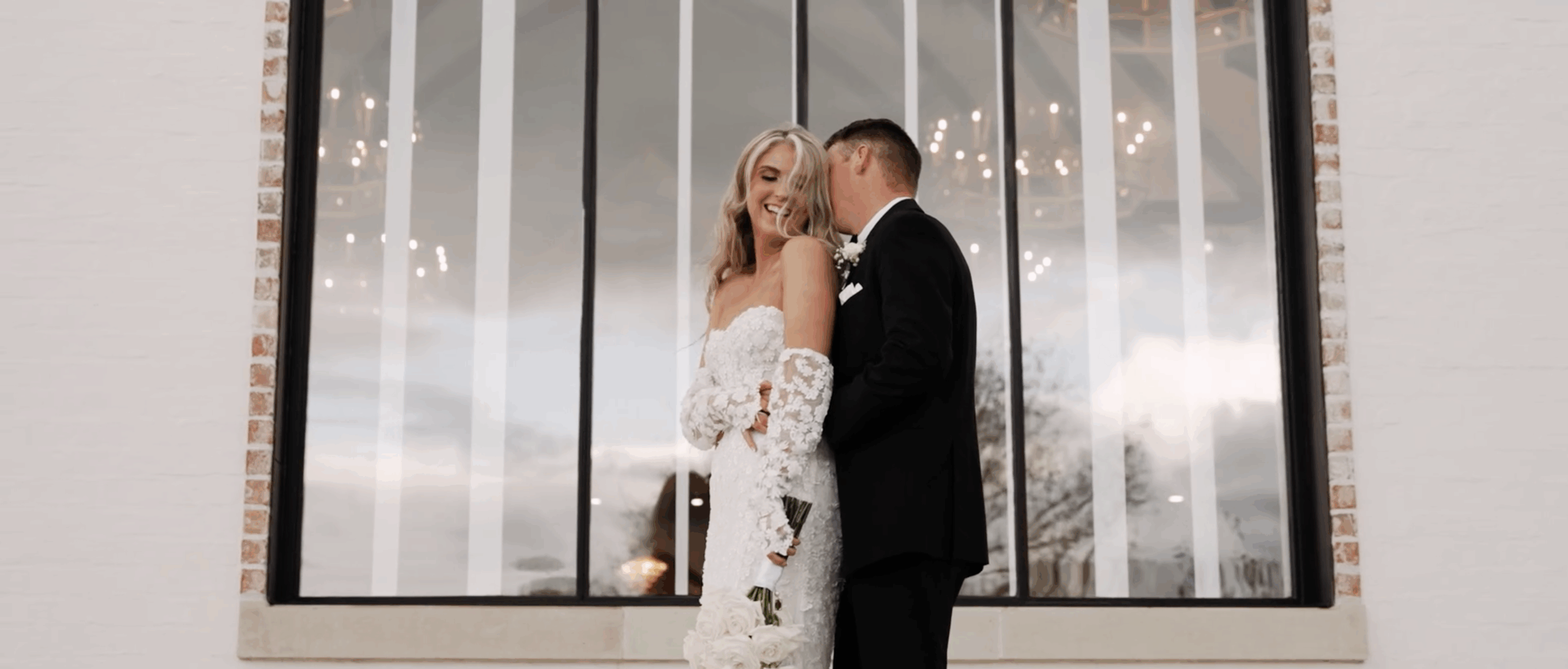 Bride giggling as her groom kisses her from behind during a joyful moment at their wedding.