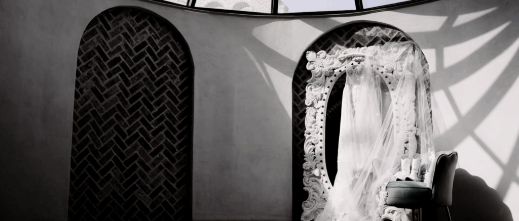 Wedding dress hanging in an outdoor space, displayed against natural light and greenery, ready for the bride.