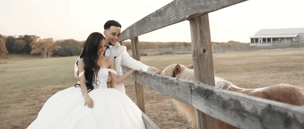 Newlyweds spend time on the farm with a horse in a fence at their venue in Houston, TX.