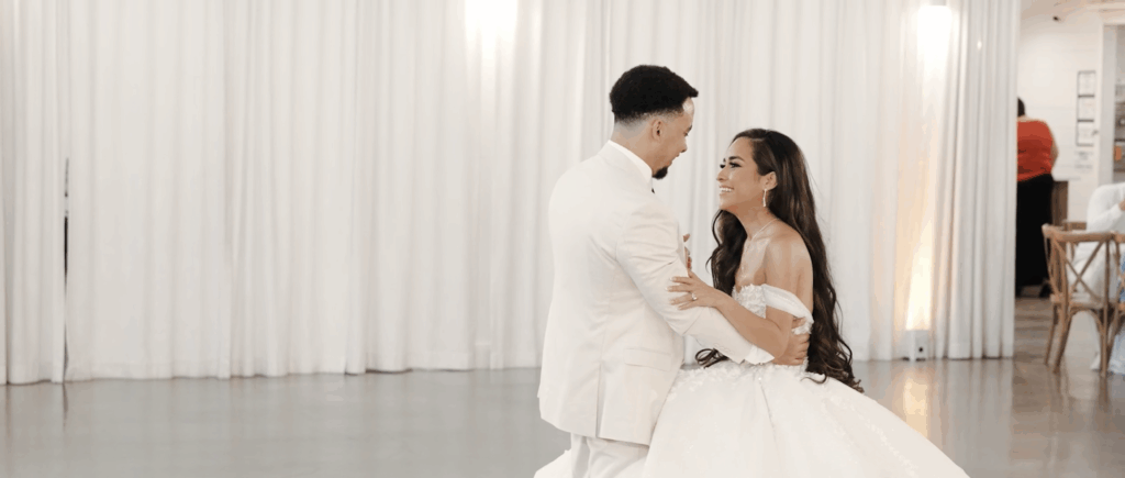 Bride and groom smile during their first dance in a wedding hall in Texas.