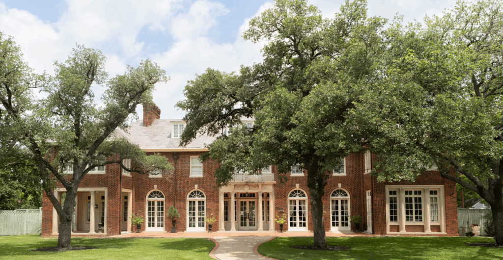 Exterior view of Astin Mansion in Bryan, Texas, a historic estate with grand columns, manicured lawns, and elegant architecture often used for weddings and events.