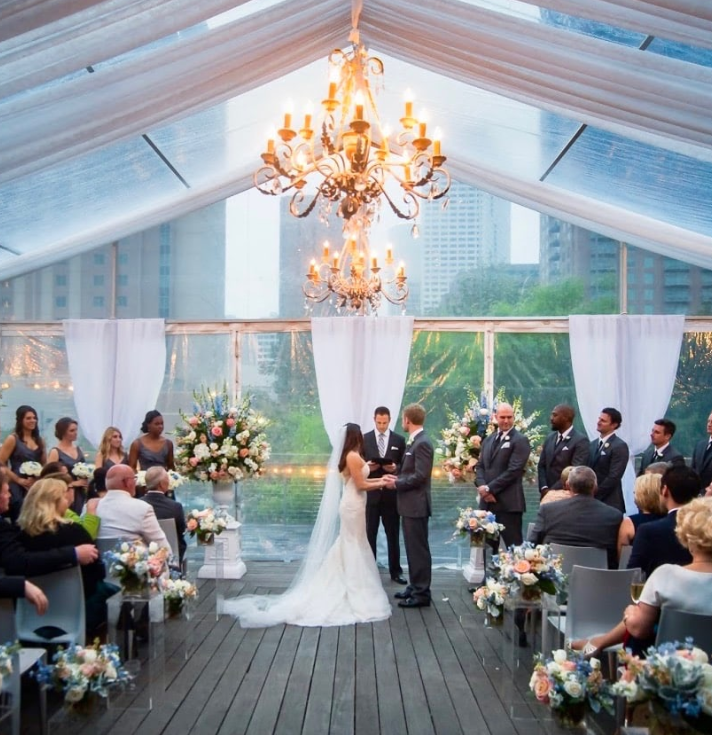 View of Discovery Green park in downtown Houston, featuring open green spaces, trees, and city skyline in the background.