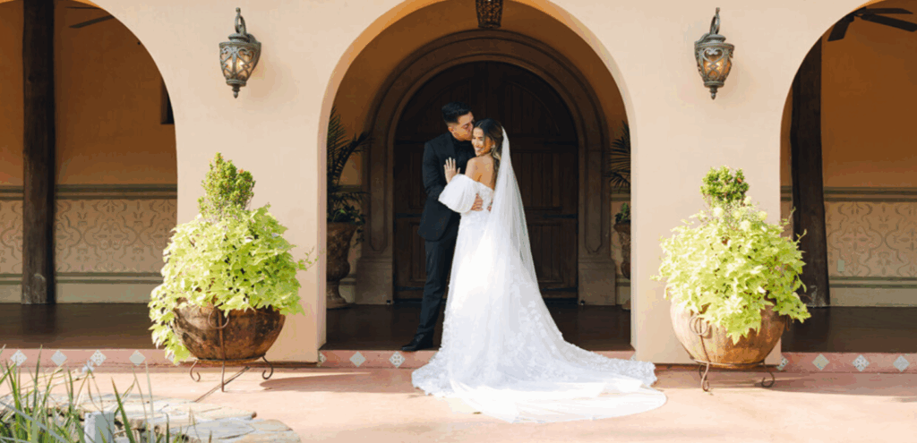 Bride and groom standing in front of Madera Estates in Houston, Texas, sharing a romantic moment outside the Spanish-style stone venue.