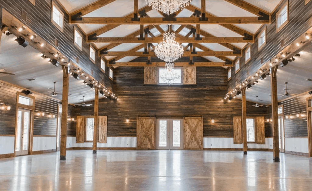 Interior of Peach Creek Ranch near Houston, featuring a rustic wooden barn-style hall with exposed beams, string lights, and polished concrete floors.