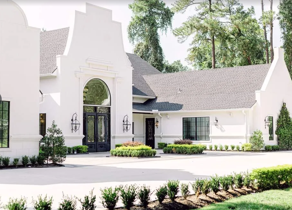 The Peach Orchard Venue near Houston, Texas — a rustic yet elegant white chapel-style building surrounded by oak trees and landscaped gardens.