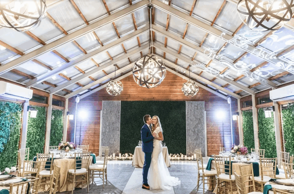 The groom kisses the bride in this natural-inspired wedding hall, The Belamour, in Houston, TX.