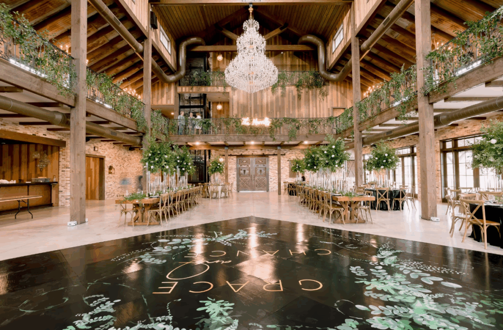 Elegant interior of The Weinberg at Wixon Valley near Houston, featuring high wooden beams, chandeliers, and large windows filling the space with natural light.