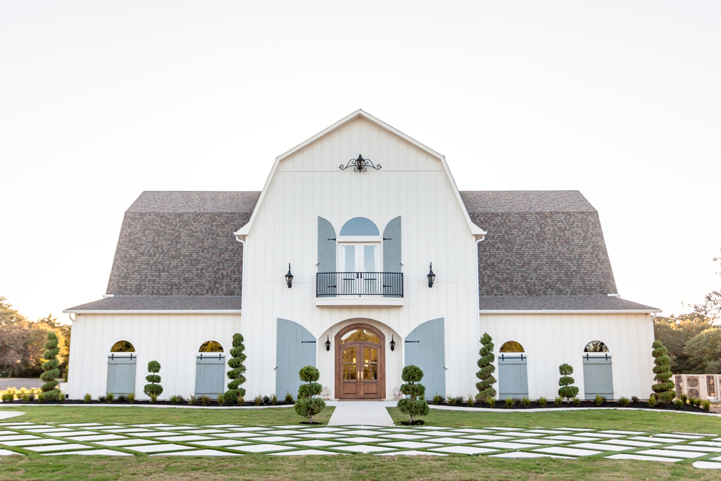 Exterior view of The French Farmhouse wedding venue near Dallas, Texas, featuring elegant white architecture, rustic charm, and manicured landscaping.
