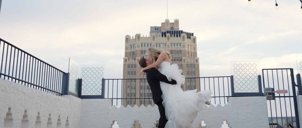 Newlyweds kiss on the rooftop of their venue in the evening in Houston, TX.