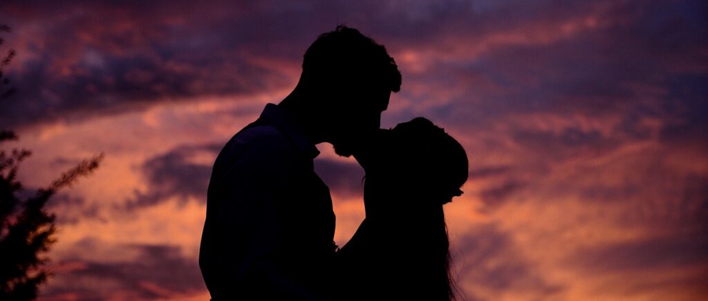 Silhouette of just married couple kissing in the evening sunset at their Dallas wedding location.