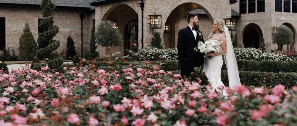 Newly married bride and groom look at each other in a garden outside of their venue.