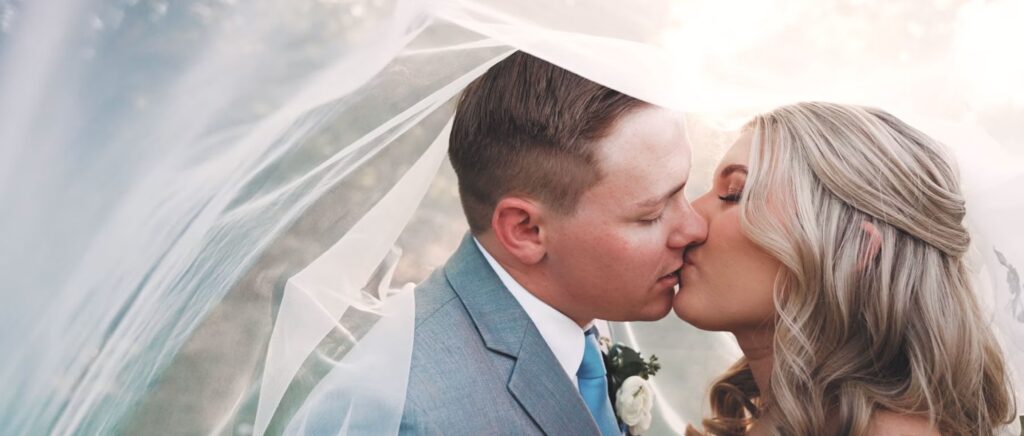 Newly married couple kisses underneath the bride's veil outside in Dallas.