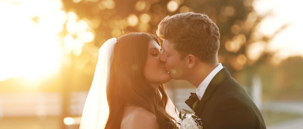 Bride and groom share a romantic kiss, capturing a joyful and intimate moment from their wedding day.