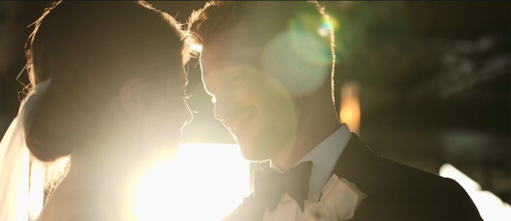 Bride and groom gazing into each other’s eyes as the sun shines through between them.